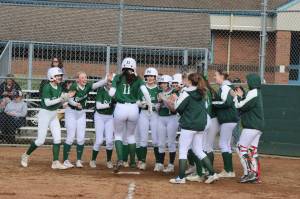 Dave Logan/for Peninsula Daily News
Port Angeles Lexie Smith jumps on home plate after hitting a grand slam home run while her teammates wait to celebrate during the Roughriders win over Sequim.
