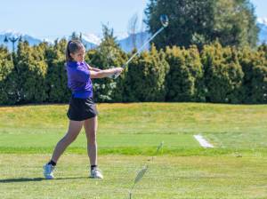 Sequims Raimey Brewer completes her swing and eyes her drive during the Wolves Olympic League girls golf match with Olympic at The Cedars at Dungeness on Thursday. (Emily Matthiessen/Olympic Peninsula News Group)