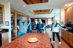 Dee Norlin, right, of Port Townsend and host at Pasture House, one of the eight homes on the AAUW Kitchen Tour on Marrowstone Island, points out the cabinetry, red alder, madrona and cedar and counter surfaces in a recently remodeled home and kitchen using the latest technologies to make the home eco-friendly and efficient. (Steve Mullensky/for Peninsula Daily News)