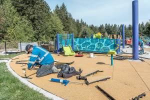 Manuel Sanchez, with MTZ Installs of Pasco, lays soft, foam tiles in the landing area of the JUMP playground area of HJ Carroll Park in Port Hadlock as part of phase two of new equipment and safety upgrades. (Steve Mullensky/for Peninsula Daily News)