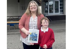 Dennis Tisdale of Queen of Angels school and his winning medal design for the North Olympic Discovery Marathon kids' marathon. With him is Queen of Angeles principal Ceci Kimball. (Port Angeles Marathon Association)