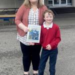 Dennis Tisdale of Queen of Angels school and his winning medal design for the North Olympic Discovery Marathon kids marathon. With him is Queen of Angeles principal Ceci Kimball. (Port Angeles Marathon Association)