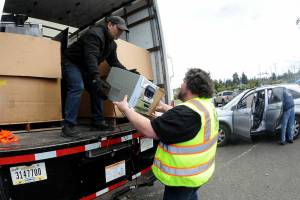 Olympic Kiwanis Club member Tobin Standley, right, hands a piece of stereo equipment to Gerald Casasola for disposal during Saturdays electronics recycling collection day in the parking lot at Port Angeles Civic Field. Items collected during the roundup were to be given to Friendly Earth International Recycling for repairs and eventual resale, or else disassembled for parts. Club members were accepting monetary donations during the event as a benefit for Kiwanis community programs. (Keith Thorpe/Peninsula Daily News)