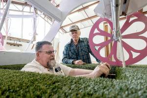 Bliss Morris of Chimacum, a float builder and driver of the Rhody float, sits in the drivers seat on Thursday as he checks out sight lines in the 60-foot float he will be piloting in the streets of Port Townsend during the upcoming 90th Rhody Parade on Saturday. Rhody volunteer Mike Ridgway of Port Townsend looks on. (Steve Mullensky/for Peninsula Daily News)