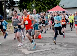 The Rhody Runs womens 10K winner, Fiona Fraser, (1131) is on the heels of her father, Ian (1132), who finished fourth among the men, as they exit the Jefferson County Fairgrounds at the start of the 44th annual Jefferson Healthcare Rhody Run on Sunday. (Steve Mullensky/for Peninsula Daily News)
