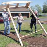 KEITH THORPE/PENINSULA DAILY NEWS
Woodworker Michael Clemens, left, with help from Christine Loewe, executive director of the Port Angeles Fine Arts Center, and fourth-grade teacher Tony Seidl, right, erect a dragon-themed arbor at the student garden at Dry Creek School on Thursday in Port Angeles.