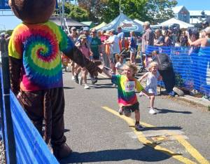 A young runner in the North Olympic Discovery Marathon's kids marathon gets a high-five at the starting line Saturday at the Port Angeles City Pier. (Pierre LaBossiere/Peninsula Daily News)