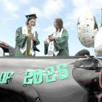 Port Angeles High School twin graduates Kaylie Mast, left, and Kendall Mast, communicate with their friends by text while waiting for the start of the 2025 graduation parade on Friday. The parade began at Ediz Hook and culminated with a formal ceremony Friday evening at Port Angeles Civic Field. (Keith Thorpe/Peninsula Daily News)