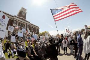 A demonstrator carrying an American flag walks the sidewalk in front of the Clallam County Courthouse on Saturday. (Keith Thorpe/Peninsula Daily News)