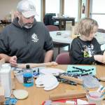 KEITH THORPE/PENINSULA DAILY NEWS
June Ward, 10, examines a wooden paddle she is decorating as her father, Jack Ward of Port Angeles, works on his own paddle during a craft-making session on Friday at the Elwha Klallam Heritage Center in Port Angeles. The paddles are among the thousands of gifts being created for participants in the 2025 Tribal Canoe Journey, hosted this year by the Lower Elwha Klallam Tribe. The event begins with the landing of dozens of native canoes at the mouth of the Elwha River on July 31 and continues with five days of celebration on the Lower Elwha reservation west of Port Angeles. As many as 10,000 indigenous peoples are expected to take part. The public is invited to help with giftmaking sessions, scheduled daily from 9 a.m. to 4 p.m. at the Heritage Center.