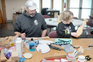 KEITH THORPE/PENINSULA DAILY NEWS
June Ward, 10, examines a wooden paddle she is decorating as her father, Jack Ward of Port Angeles, works on his own paddle during a craft-making session on Friday at the Elwha Klallam Heritage Center in Port Angeles. The paddles are among the thousands of gifts being created for participants in the 2025 Tribal Canoe Journey, hosted this year by the Lower Elwha Klallam Tribe. The event begins with the landing of dozens of native canoes at the mouth of the Elwha River on July 31 and continues with five days of celebration on the Lower Elwha reservation west of Port Angeles. As many as 10,000 indigenous peoples are expected to take part. The public is invited to help with giftmaking sessions, scheduled daily from 9 a.m. to 4 p.m. at the Heritage Center.