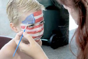 KEITH THORPE/PENINSULA DAILY NEWS
Zane Rensen, 6, of Port Angeles receives patriotic face paint from Port Angeles High School cheerleader Madison Bishop in the children's activity tent at Port Angeles City Pier during Friday's Independence Day celebration.