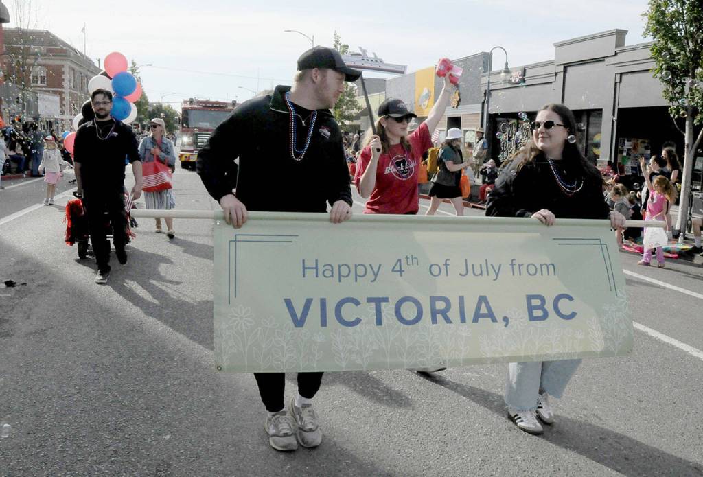 A contingent of visitors from Victoria march with the grand marshals parade entry celebrating the Black Ball Ferry Line and the longstanding cultural and economic ties forged by the Coho ferry. (Keith Thorpe/Peninsula Daily News)