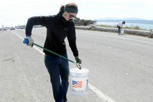 Emily Simmons of Port Angeles, a member of the Surfriders Foundation, collects fireworks debris from along Ediz Hook Road in Port Angeles on Saturday. Although fireworks have been banned in the city of Port Angeles, many people used them illegally, leaving behind trash and spent casings and tasking volunteers to pick up the remains. A group from 4PA performed similar cleanup duty on another portion of the hook. (Keith Thorpe/Peninsula Daily News)