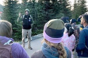 John Goar speaks to a group of visitors before leading them on a moonlit hike up Hurricane Hill for a tour of the constellations. Goar is a volunteer who leads the full moon hikes and dark sky telescope tours that are part of the astronomy program at Hurricane Ridge. (Paula Hunt/Peninsula Daily News)