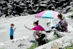 Lisa Hansen of Port Angeles, center, takes a cellphone photo of her son, Cooper Hansen, 3, as Hansens mother, Tracy Hansen, right, looks on during a warm day at Hollywood Beach on the Port Angeles waterfront on Wednesday. The trio were enjoying a sunny summer afternoon next to the water. (Keith Thorpe/Peninsula Daily News)