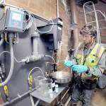 Ben Hecht, a geologist with environmental consulting firm Landau Associates, takes a sample of raw drinking water taken at the city of Port Angeles ranney collector on Saturday at the Elwha River, downstream from Fridays tanker crash that dumped petroleum products into Indian Creek west of Port Angeles. (Keith Thorpe/Peninsula Daily News)