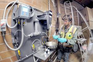 Ben Hecht, a geologist with environmental consulting firm Landau Associates, takes a sample of raw drinking water taken at the city of Port Angeles ranney collector on Saturday at the Elwha River, downstream from Fridays tanker crash that dumped petroleum products into Indian Creek west of Port Angeles. (Keith Thorpe/Peninsula Daily News)