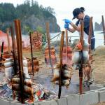 With the Quillayute River flowing toward James Island and the Pacific Ocean, Quileute tribal member Smokey Ward prepares baked salmon in the traditional way Saturday morning during the Quileute Days celebration in La Push. A large crowd gathered for the festival. (Lonnie Archibald/for Peninsula Daily News)