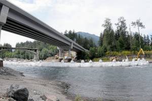 A state Department of Transportation crew constructs a temporary diversion dam under the former and current U.S. Highway 101 bridges on Saturday in preparation for the demolition of the old bridge. (Keith Thorpe/Peninsula Daily News)