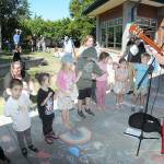 Youngsters gather on the lawn of the Port Angeles Public Library to listen to childrens entertainer Eli Rosenblatt of Seattle as part of the Port Angeles Parks and Recreation Departments citywide Day of Play. The Saturday event featured a variety of activities for children and their parents at venues across the city. (Keith Thorpe/Peninsula Daily News)