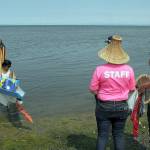 Jamestown SKlallam tribal members Loni Greninger, left, and Jesse Osmer greet members of the Kwumut Lelum youth canoe from a collection of First Nation tribes of eastern Vancouver Island as they arrive at Jamestown Beach near Sequim as part of the 2025 Canoe Journey to Elwha. About 40 canoes were expected to land at Jamestown on their way to a mass landing today at the Lower Elwha Klallam Tribe. (Keith Thorpe/Peninsula Daily News)