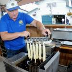 Port Angeles Lions Club member Kevin Borde dips batter-coated jumbo hot dogs into a fryer to make corn dogs at the clubs food stand at the Clallam County Fair on Friday. (Keith Thorpe/Peninsula Daily News)