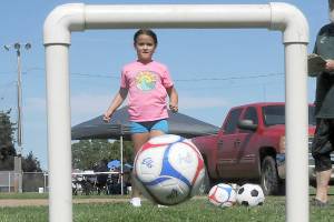 Kyra Toner, 8, of Burien kicks a soccer ball through a narrow goal as part of an informal soccer skills test during Saturdays Party at the Park at Elks Playfield in Port Angeles. The event, hosted by the Port Angeles Naval Elks Lodge, featured a variety of activities for children and adults, food and live music. (Keith Thorpe/Peninsula Daily News)