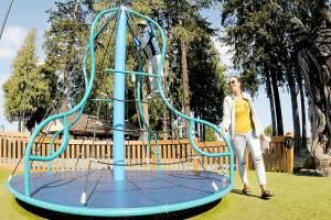 Carlyn Beebe of Forks pushes a merry-go-round toy as her son, Lane, 6, takes a ride on Tuesday at the Dream Playground at Erickson Playfield in Port Angeles. The pair took time out from errands for a visit to the popular park. (Keith Thorpe/Peninsula Daily News)