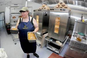 Kate Orzikh, owner of Sunflower Tastes bakery and deli at The Wharf in Port Angeles, holds loaves of sourdough bread created in the establishments kitchen. (Keith Thorpe/Peninsula Daily News)