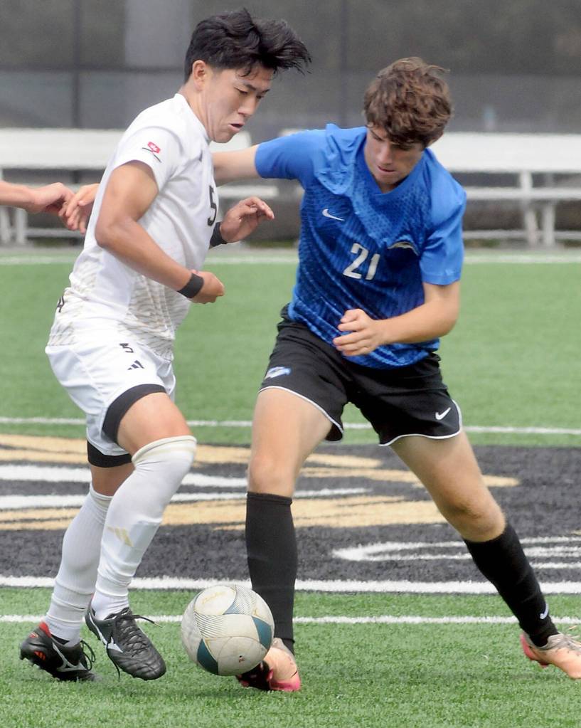 KEITH THORPE/PENINSULA DAILY NEWS Peninsulas Rei Sato, left, fends off Rogues Maximo Melgar-Martich during Fridays match in Port Angeles.