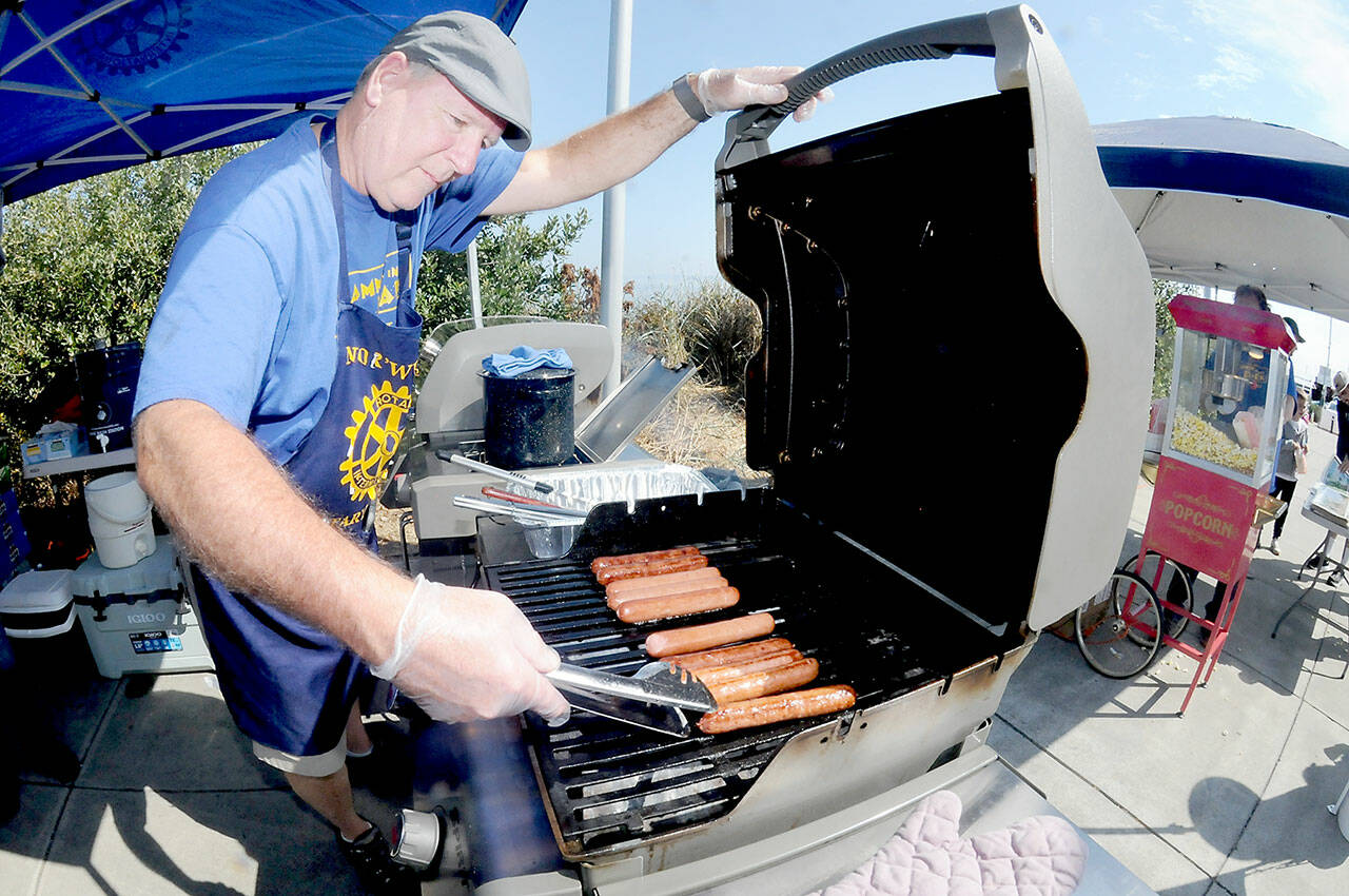 Chris Szczetczynski, president of the NorWester Rotary Club, cooks hot dogs for festival-goers during Saturdays Jammin in the Park at Pebble Beach Park in Port Angeles. The event, hosted by the Rotary Club and Koenig Subaru, featured an afternoon of music, a car show, food and childrens activities. (Keith Thorpe/Peninsula Daily News)