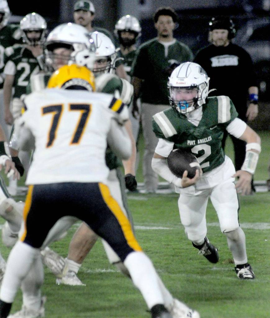 Port Angeles quarterback Carson Waddell, right, looks for a way past the Forks defense, including defensive lineman Landon Thomas, front. (KEITH THORPE/PENINSULA DAILY NEWS)