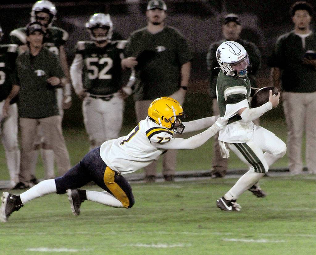KEITH THORPE/PENINSULA DAILY NEWS
Port Angeles quarterback Carson Waddell, right, tries to avoid the pursuit of Forks' Landon Thomas on Friday night in Port Angeles.