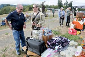 Tim Blair and Amy Peterson, both of Port Townsend, make a purchase from a table of random sale items during Saturdays Great Strait Sale at a community vending location in Joyce. The annual event featured dozens of yard and garage sales stretching along state Highway 112 from Port Angeles to Neah Bay. (Keith Thorpe/Peninsula Daily News)