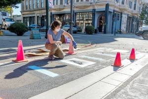 Connie Segal of Port Townsend spray paints a graphic by local artist Timbul Cahyono on the crosswalk at Taylor and Water streets in downtown Port Townsend on Wednesday. The graphics are outside the Port Townsend Film Festivals temporary lounge on the corner and make for a light-hearted entrance to the festival, which will host its Opening Night gala tonight. Films will be screened from Friday through Sunday at various locations. (Steve Mullensky/for Peninsula Daily News)