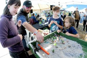 Naturebridge educators Ana Shinal, left, and Zach Drake demonstrate how water erosion affects the landscape in a test farm assembled by Wyatt Lutrz, 10, and Westley Lutz, 7, at a hands-on display set up by the Naturbridge educational organization at the fourth annual Forever StreamFest on Saturday at Pebble Beach Park in Port Angeles. The environmentally themed festival, hosted by the Port Angeles Garden Club, featured dozens of information booths, displays and youth activities, as well as food, music and a beer garden. (Keith Thorpe/Peninsula Daily News)