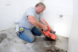 Retired plumber John Gilbertson cuts out a soil pipe in the process of removing one of a pair of toilets in the public restroom at Lincoln Park in Port Angeles. Members of North Olympic Baseball & Softball are converting the restroom to be compliant with Americans with Disabilities Act guidelines on handicap accessibility, removing a toilet for improved space on the womens side and adding handrails to both sides, as well as installation of wider access doors and other upgrades. The restroom will serve the nearby Lincoln Park athletic fields. (Keith Thorpe/Peninsula Daily News)