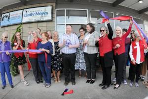 Peninsula Daily News Editor Brian McLean and Publisher Eran Kennedy cut ceremonial ribbons on Thursday in front of the newspapers new building at 1102 E. First St. in Port Angeles. Newspaper employees and ambassadors from both the Port Angeles and Sequim-Dungeness chambers of commerce celebrated the event. (Peninsula Daily News)