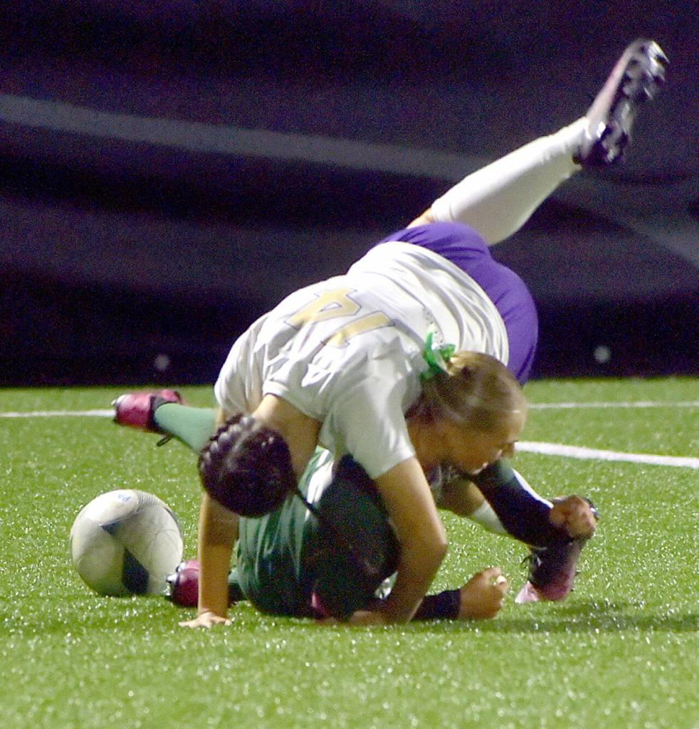 KEITH THORPE/PENINSULA DAILY NEWS
Port Angeles' Teanna Clark hits the pitch as Sequim's (#14) tumbles on top of her for a penalty on Thursday night at Peninsula College.