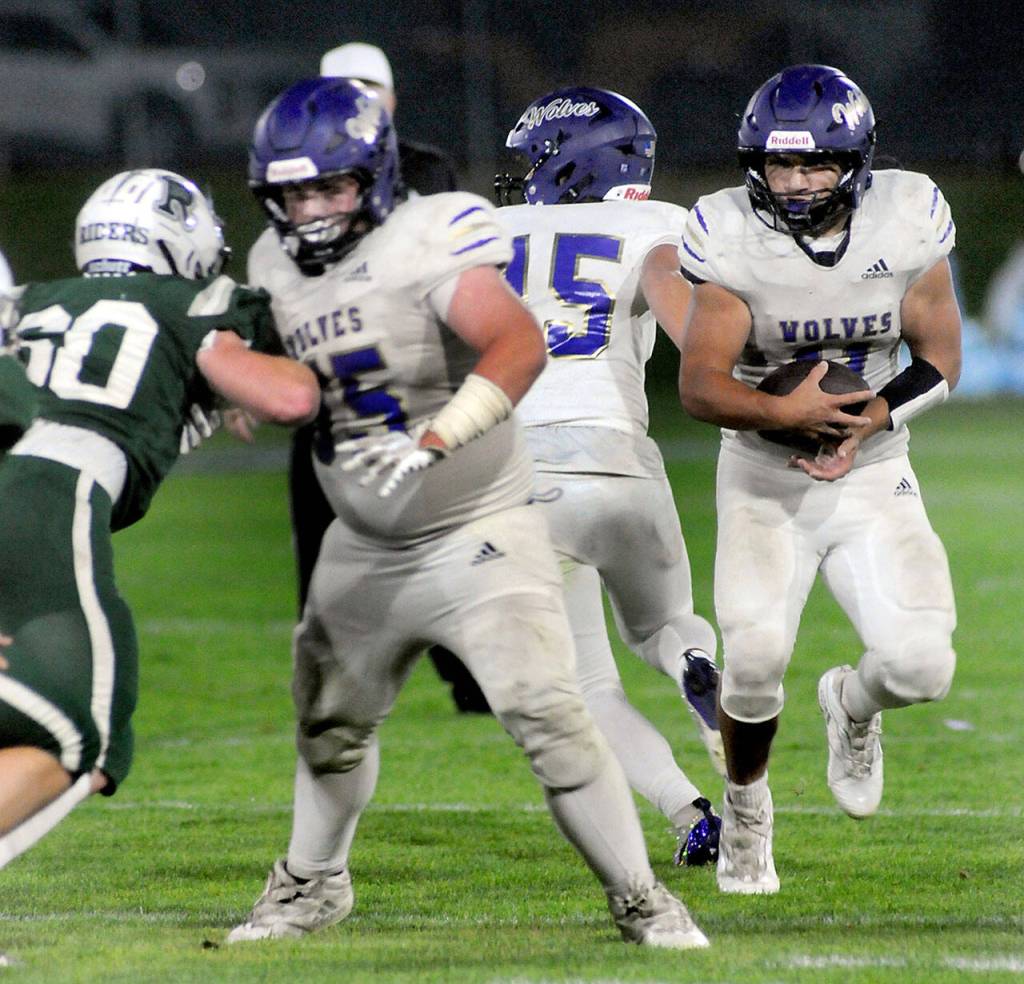 KEITH THORPE/PENINSULA DAILY NEWS
Sequim's Liam Walker, right, takes the handoff from quarterback Kaden Miller and looks for a break in the defensive line, including Port Angeles' Quinn Messersmith, left, and Sequim's Eli Miller on Friday at Port Angeles Civic Field.