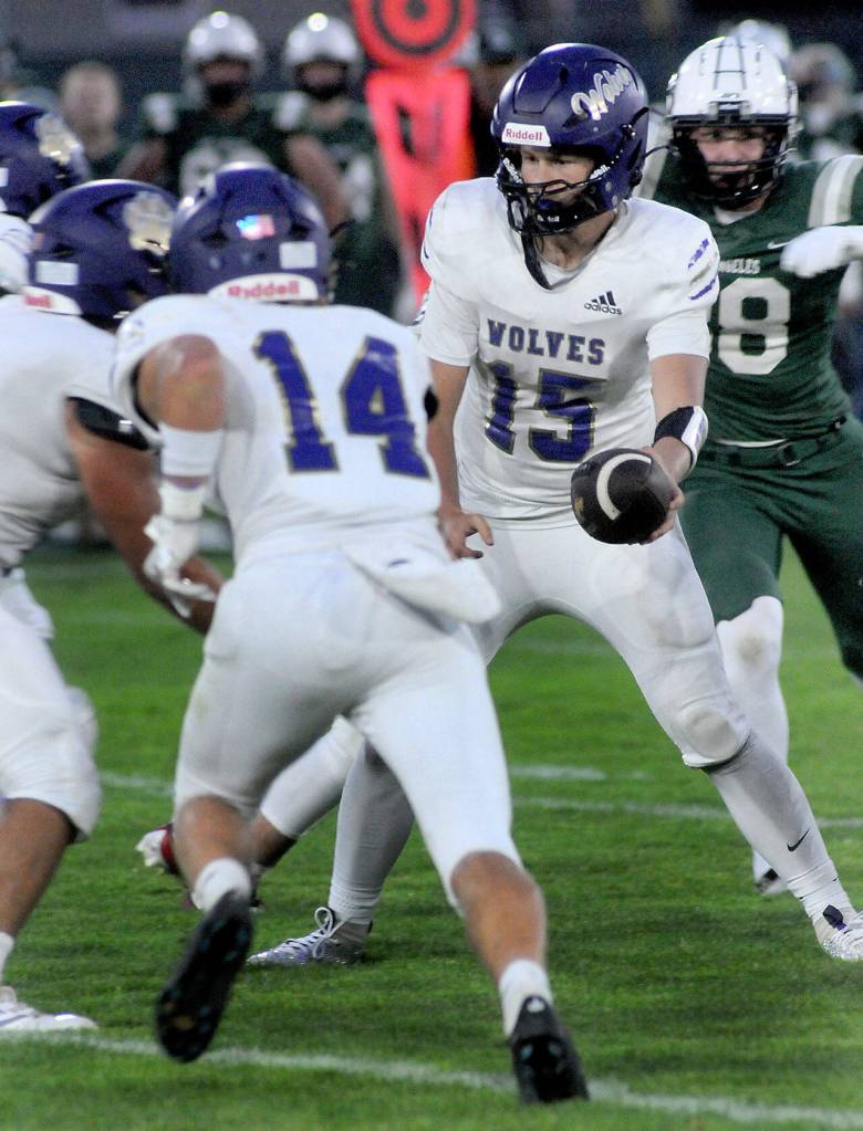 KEITH THORPE/PENINSULA DAILY NEWS Sequim quarterback Kaden Miller prepares to hand off to teammate Liam Wiker, left, protected by Zeke Schmadeke as Port Angeles Taylor Abold closes in during Fridays game in Port Angeles.