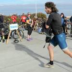 KEITH THORPE/PENINSULA DAILY NEWS Big Hurt iron man competitor Joey Gish of Sequim races through the transfer zone on the way to his kayak after finishing the mountain bike leg of the race in first place on Saturday at Pebble Beach Park in Port Angeles. Gish finished second to Michael Finley, who won the race for the fourth time.