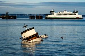 East Jefferson Fire Rescue and the state Department of Ecology responded Sunday to a sunken cabin cruiser that went aground off Indian Point between the ferry dock and Port Townsend Marina. One person on board was treated for injuries. The Washington State Ferry M/V Salish is entering the dock. (Steve Mullensky/for Peninsula Daily News)
