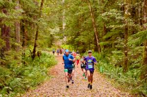 Competitors in the first Spruce Railroad Trail 5K/10K in 2024 run down a leaf-covered path along Lake Crescent. (Matt Sagen/Cascadia Films)
