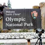 Lorena Miramontes Morley, left, and her spouse, Mandy Miramontes Morley, both of Anaheim, Calif., use a remote-controlled camera to take a self-portrait on the Olympic National Park entrance sign on Tuesday in Port Angeles. (Keith Thorpe/Peninsula Daily News)