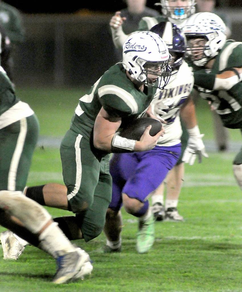 KEITH THORPE/PENINSULA DAILY NEWS Port Angeles Dylan Mann breaks through the North Kitsap defensive line, including Viking lineman Andrew Knott with assistance from Manns teammate, Lane Wilson, right, on Friday in Port Angeles.
