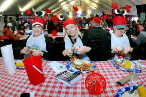 Festival-goers, from left, Cara Saunto, Shelby Damiani and Adrienne Bohannon, all of Seattle, crack into their crab dinners on Saturday at the Dungeness Crab Festival on the Port Angeles waterfront. The annual event drew thousands of visitors to downtown Port Angeles for a variety of seafood delights, music, cooking demonstrations, a craft fair and other activities. (Keith Thorpe/Peninsula Daily News)