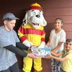 Matthew Nash/Olympic Peninsula News Group
Pizza fans Preet Saran, 10, and Jess Saran, 6, on right, receive free pizza from Dominos delivery driver Ryan Lang and Sparky the Fire Dog on Oct. 8 as part of Fire Prevention Week efforts by Clallam County Fire District 3. Staff and volunteers, in partnership with Sequim Dominos, checked homeowners smoke alarms, and if they worked, they received their orders for free.