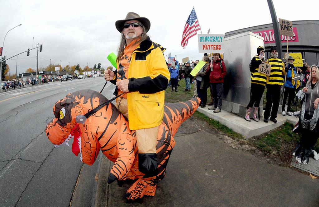 Stephen White of Port Angeles displays his inflatable T-Rex costume during Saturdays No Kings rally at the junction of First and Front streets in Port Angeles. More than 1,000 attended the rally, one of two that day in Port Angeles protesting President Donald Trump and his administration. (Keith Thorpe/Peninsula Daily News)